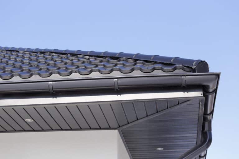 Corner of the new modern house with gutter, roof, wall and lamps.